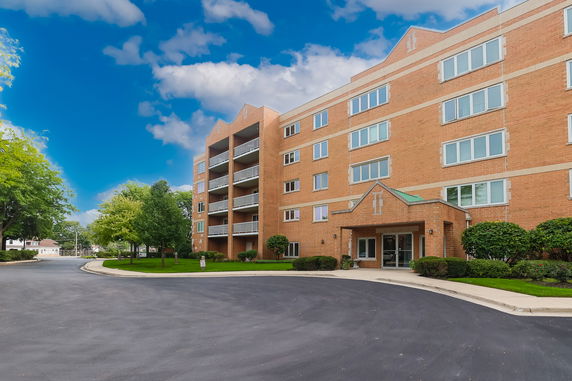 Front view of a multi-story brick apartment building with balconies.