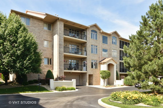 Front view of a multi-story apartment building with balconies and brick exterior.