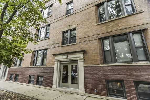 Front view of a multi-story brick building with several windows.