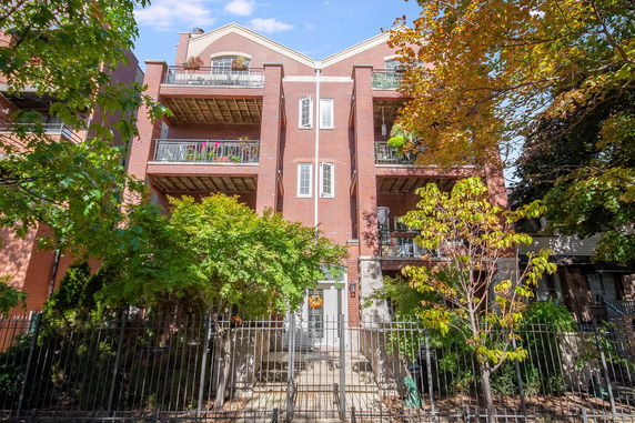Front view of a multi-story brick apartment building with balconies.