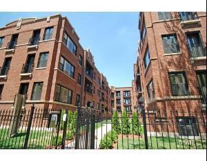 Front view of red brick multi-story apartment buildings with metal fencing.
