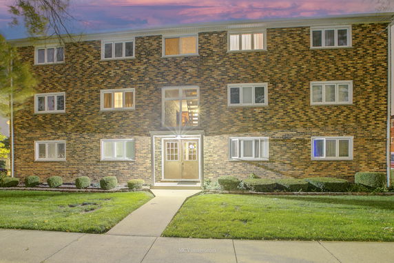 Front view of a three-story brick apartment building with multiple windows.