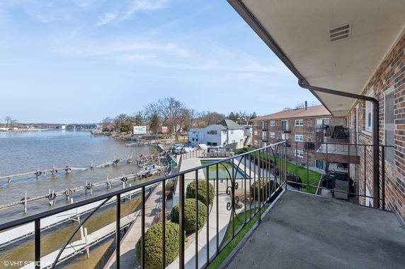 View from a balcony overlooking a waterfront and nearby buildings.