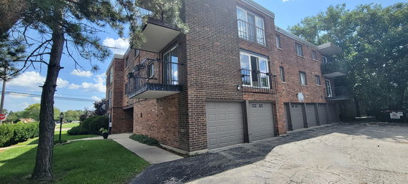 Front view of a brick multi-story building with balconies and garages.