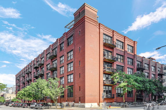 Front view of a red brick multi-story building with balconies.