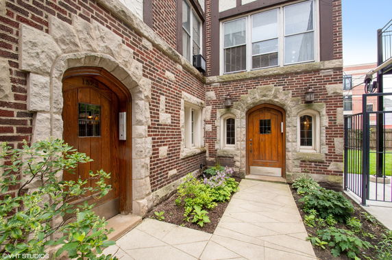 Front view of a brick building with wooden doors and stone archways.