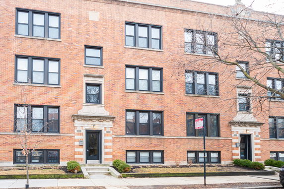 Front view of a multi-story brick apartment building with multiple windows.