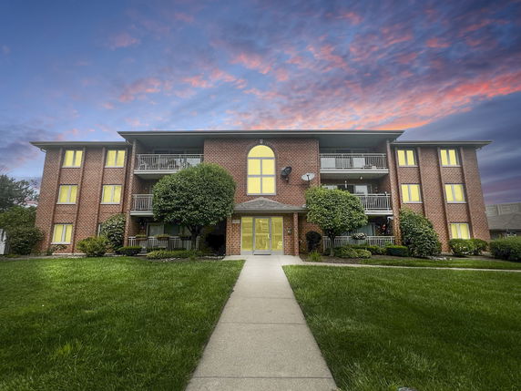 Front view of a multi-story brick building with balconies and a central entrance.