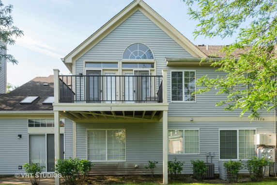 Front view of a two-story house with a balcony and large windows.
