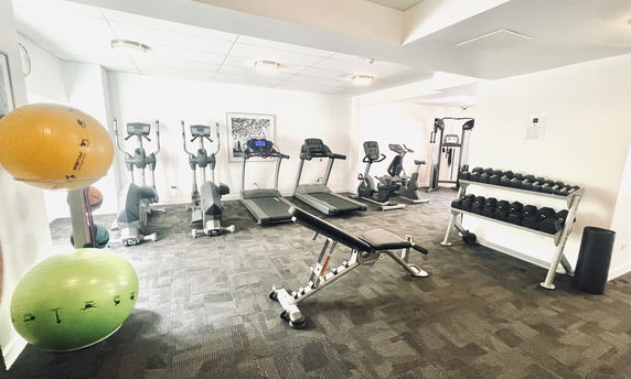 Indoor gym with exercise equipment including treadmills, stationary bikes, and weights.