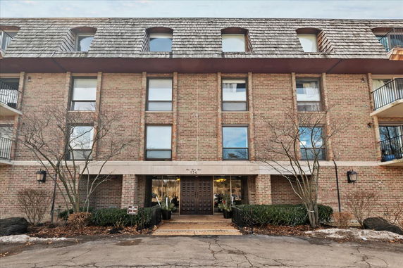 Front view of a multi-story brick building with a wooden shingled roof.