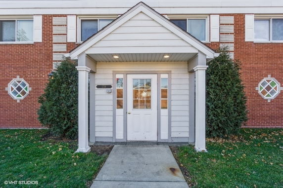 Front view of a brick building with a covered entrance and white trim.