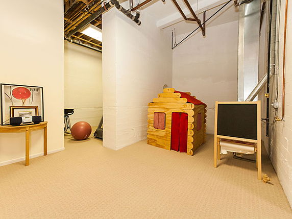 Indoor play area with a small wooden playhouse and exercise equipment in a room.