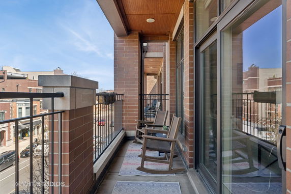 Balcony with a view of surrounding urban area, featuring chairs and railings.