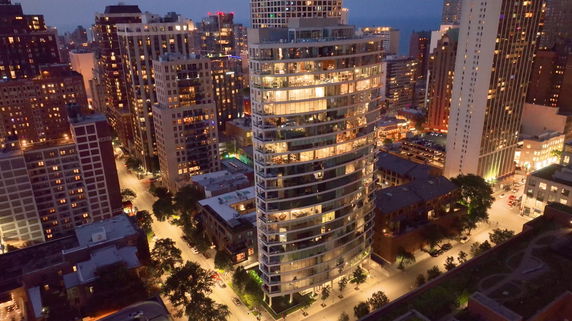 Elevated view of a modern high-rise building surrounded by cityscape at night.