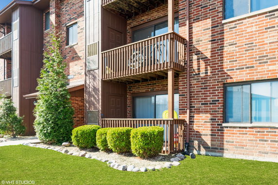 Front view of a multi-story brick apartment building with balconies.