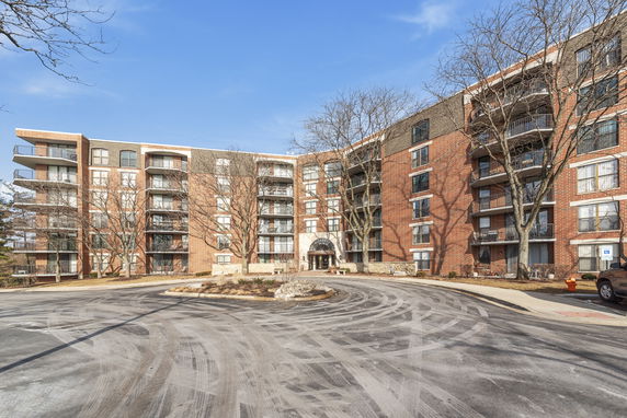 Front view of a multi-story brick apartment building with balconies.