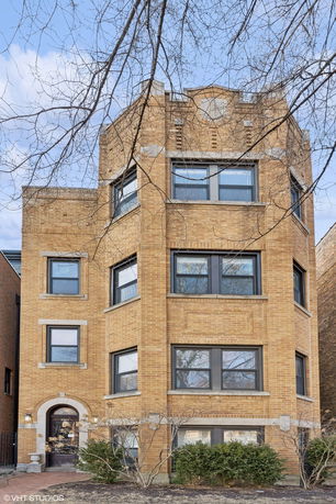 Front view of a multi-story brick building with multiple windows.