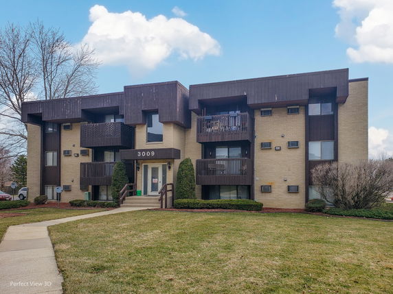 Front view of a multi-story brick apartment building with balconies.