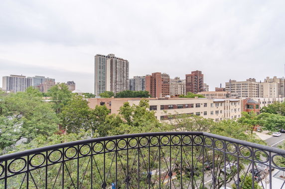 Panoramic view from a balcony overlooking a cityscape with multiple buildings.