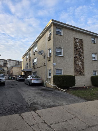 Front view of a three-story apartment building with a parking area.
