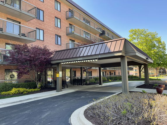 Front view of a multi-story brick building with balconies and a covered entrance.