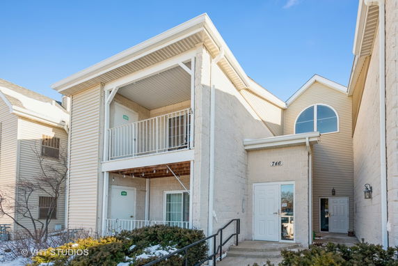Front view of a two-story building with a balcony and an entrance door.