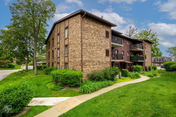 Front view of a multi-story brick apartment building with balconies.