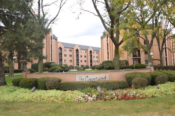 Front view of a multi-story apartment building with landscaped garden.