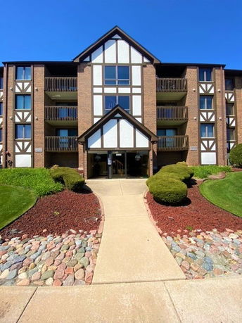 Front view of a multi-story apartment building with a central entrance and balconies.