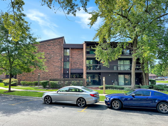 Front view of a multi-story brick apartment building with balconies.