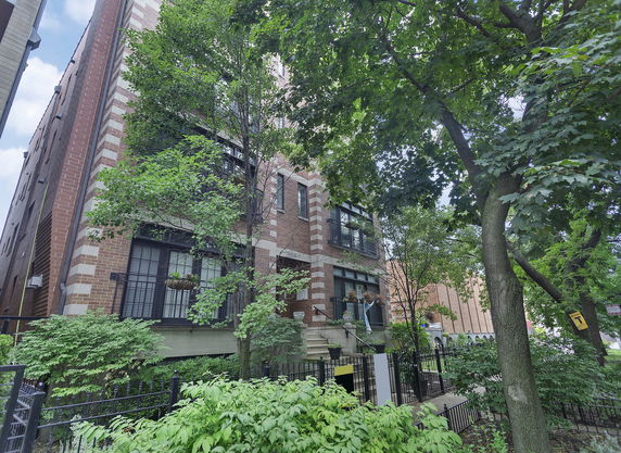 Front view of a multi-story brick building with large windows and a staircase leading to the entrance.