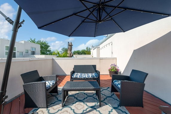 Rooftop seating area with wicker furniture and a large umbrella