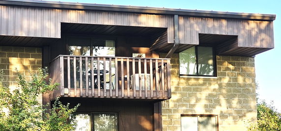 Front view of a building with a balcony and wooden railing.