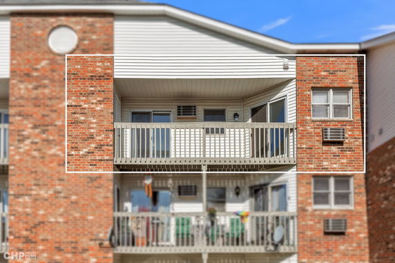 Front view of a multi-story building with brick facade and balconies.