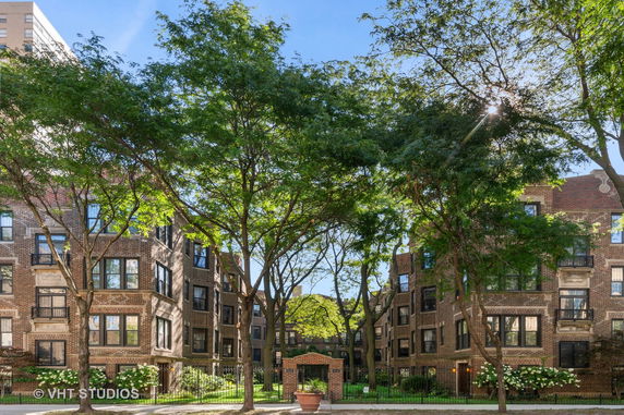 Front view of a multi-story brick residential building with large trees nearby.