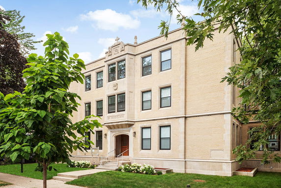 Front view of a three-story brick building with multiple windows and an entrance.