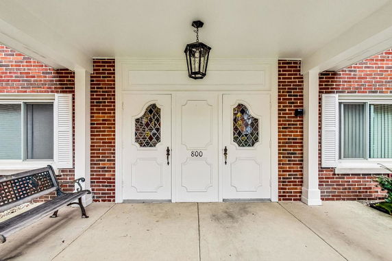 Front view of an entrance with white double doors and brick exterior.