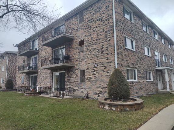 Front view of a multi-story brick apartment building with balconies.
