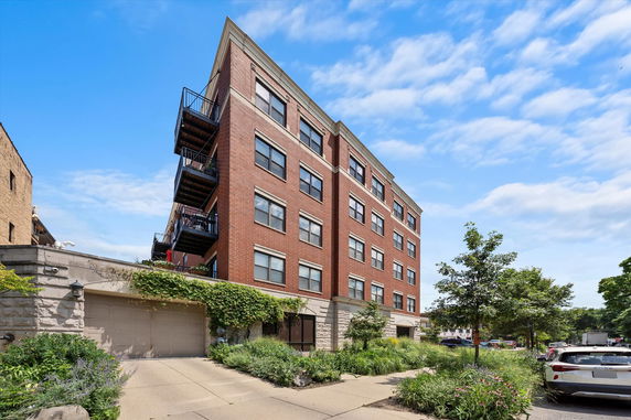 Front view of a multi-story brick apartment building with balconies.