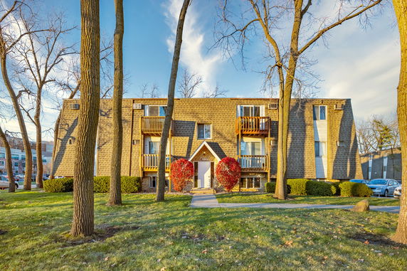 Front view of a multi-story apartment building with balconies and a central entrance.