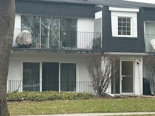 Front view of a two-story house with balconies and large windows.