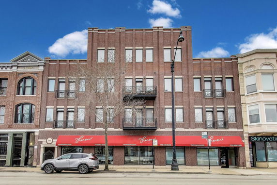 Front view of a multi-story brick building with red awnings.
