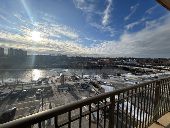 Panoramic view of a river with surrounding cityscape, seen from a balcony.