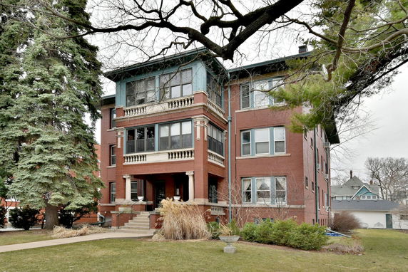 Front view of a multi-story brick building with decorative columns and large windows.