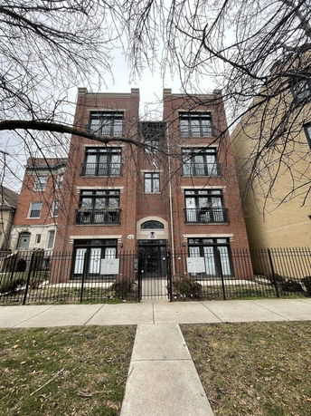 Front view of a multi-story brick building with iron gates and multiple windows.
