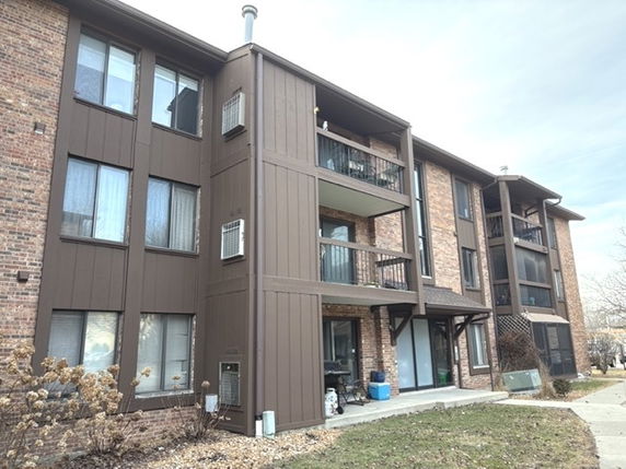 Front view of a multi-story apartment building with balconies and brick facade.