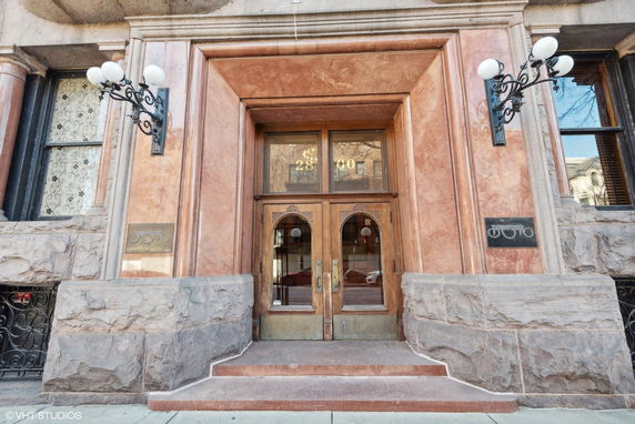 Front view of a building entrance with decorative stonework and ornate wooden doors.