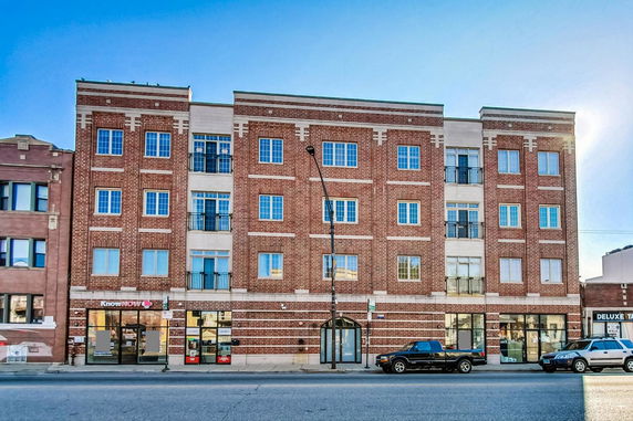 Front view of a multi-story brick building with retail spaces on the ground floor.
