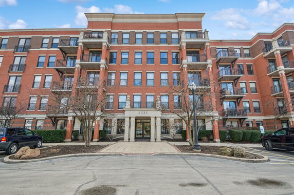 Front view of a multi-story brick apartment building with balconies.